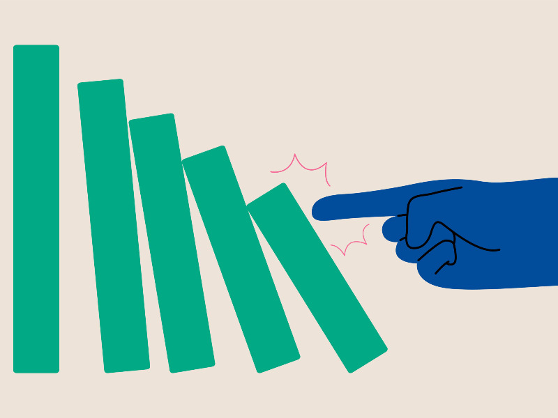 Eine Hand stößt einen Dominostein an, der umkippt. Die nächsten Dominosteine beginnen auch zu kippen.