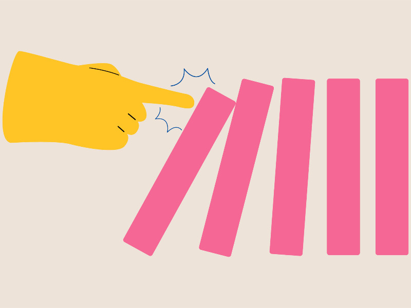 Eine Hand stößt einen Dominostein an, der umkippt. Die nächsten Dominosteine beginnen auch zu kippen.