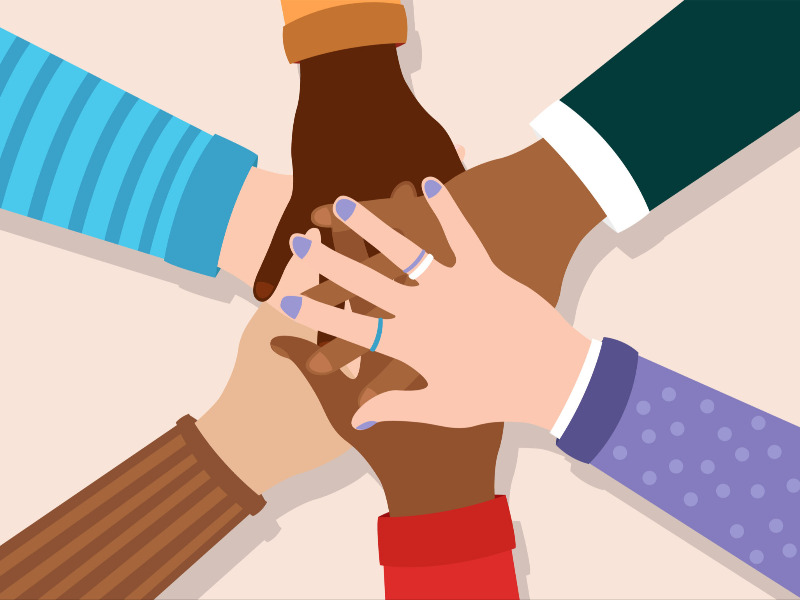 Group of diverse hands coming together in unity and solidarity stacking on top of each other